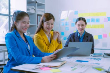 Asyalı iş kadınlarından oluşan bir grup başarılı takım çalışmalarını gösteren grafikler ve grafikler, şirket büyüme hedefleri, bilgisayar ekranlarındaki sunumlar hakkında görüştü.