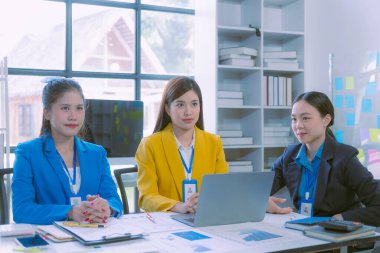 Asyalı iş kadınlarından oluşan bir grup başarılı takım çalışmalarını gösteren grafikler ve grafikler, şirket büyüme hedefleri, bilgisayar ekranlarındaki sunumlar hakkında görüştü.