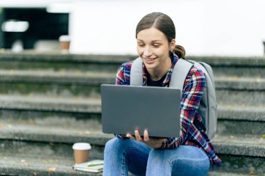 Genç kız üniversite öğrencisi internette bilgi arıyor, arkadaşlarıyla sohbet ediyor araştırma yapmak, çalışmak ya da teknoloji hakkında bilgi edinmek için parka gidiyor..