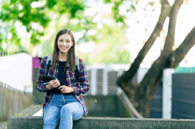 Genç kız üniversite öğrencisi internette bilgi arıyor, arkadaşlarıyla sohbet ediyor araştırma yapmak, çalışmak ya da teknoloji hakkında bilgi edinmek için parka gidiyor..