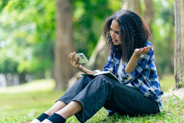 Elinde akıllı telefon olan zenci bir üniversite öğrencisi arkadaşlarıyla internette sohbet edip dışarıda aktiviteler yapıyor.