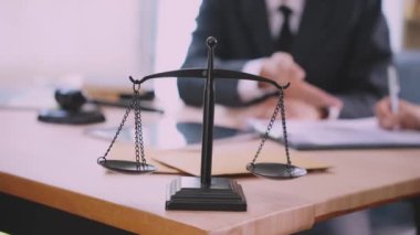Avukatlar çekiç ve adalet terazisiyle büroda yasal belgeleri tartışıyorlar. Danışma ve hukuk kavramının buluşması, adaletin terazisiyle yargılama.