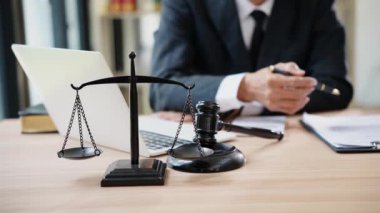 Avukatlar çekiç ve adalet terazisiyle büroda yasal belgeleri tartışıyorlar. Danışma ve hukuk kavramının buluşması, adaletin terazisiyle yargılama.