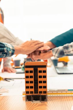 Mimar ve inşaat mühendisi el ele tutuşuyor, takım olarak çalışıyor ve ev planlarıyla masaya yakın dikey resim çekildikten sonra iş birliği konsepti oluşturuyor.