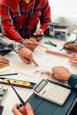İnşaat konsepti: Mühendisin elleri, mimari planlar üzerine kat planlarını tartışan mimari ekipmanlarla mavi baskının üzerine planlar çiziyor. Dikey resmi kapat