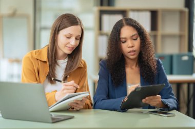 Birlikte çalışmaktan bahsederken iki güzel iş kadını laptoplarla birlikte çalışıyor. Toplantılar ve planlama tartışmaları yeni şirketin stratejisini tartışıyor.