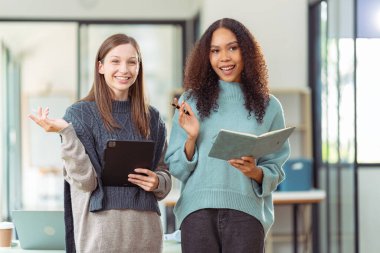 İki kız öğrenci bir kafede birlikte çalışıyor, sohbet ediyor ve projeleri tartışıyorlar. İnternette bilgi arayan bir dizüstü bilgisayarla.