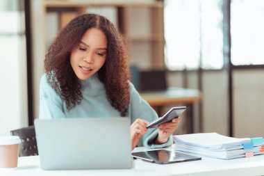 Masada oturan güzel Afrikalı kız dizüstü bilgisayara bakarken iyi haberlerle dolu bir e-posta mesajını okumaktan mutlu görünüyor. İnternette müşterilerle sohbet et.