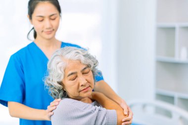 Yaşlı bir Asyalı kadın hasta mutlu ve gülümsüyor, onu yürümesi için fiziksel terapi yapmaya teşvik ediyor ve destekliyor. Sağlık hizmeti kavramı