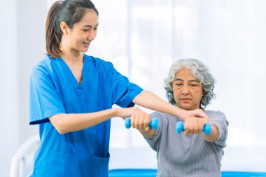 Yaşlı bir Asyalı kadın hasta mutlu ve gülümsüyor, onu yürümesi için fiziksel terapi yapmaya teşvik ediyor ve destekliyor. Sağlık hizmeti kavramı