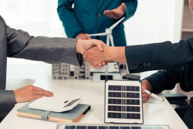 Bir emlakçı ile arka planda küçük bir ev planı olan bir iş adamı arasındaki yakın çekim. Gayrimenkul, konut, işlem, sözleşme kavramları.