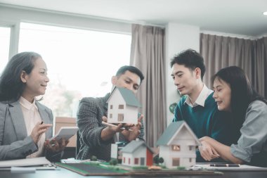 Ahşap ev modelleriyle belgeler, dizüstü bilgisayarlar ve tek aile inşaat evindeki evleri tartışan insanlar ile gayrimenkul işi toplantısı, malzeme ve konut projeleri için konut seçimleri