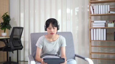 Kanepede tablet kullanan Asyalı kadın internet sörf ekranında yazılan metne bakın. Sosyal medya, çevrimiçi alışveriş teknolojisi kavramı