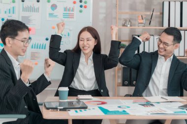 İş adamlarından oluşan bir ekip iş toplantısını alkışlamak için ellerini kaldırıyor. İş başarısını destekliyor ya da kutluyor..