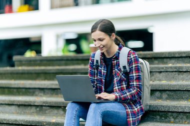 Üniversite öğrencileri teknoloji öğrenme fikirlerini tartışmak için dışarıda dizüstü bilgisayar ve tabletlerle çalışıyorlar..