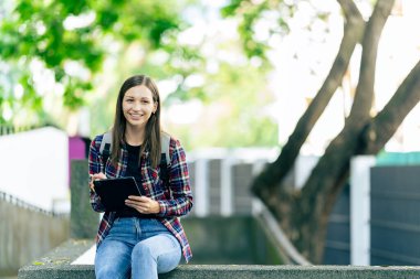 Üniversite öğrencileri teknoloji öğrenme fikirlerini tartışmak için dışarıda dizüstü bilgisayar ve tabletlerle çalışıyorlar..