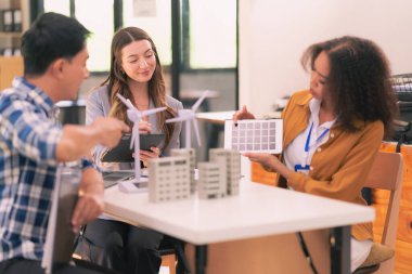 Bir satış temsilcisi, ofisteki iş arkadaşlarına güneş pillerinin nasıl çalıştığıyla ilgili bir sunum yapıyor. Güneş paneli pil konsepti üzerinde çalışan yenilenebilir enerji mühendislerinden oluşan bir ekiple toplantı..