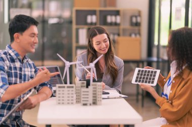 Bir satış temsilcisi, ofisteki iş arkadaşlarına güneş pillerinin nasıl çalıştığıyla ilgili bir sunum yapıyor. Güneş paneli pil konsepti üzerinde çalışan yenilenebilir enerji mühendislerinden oluşan bir ekiple toplantı..