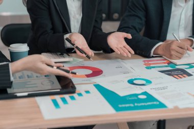 İş adamları başarılı takım çalışmalarının ve fabrika ofisinde beyin fırtınalarının sonuçlarını gösteren çizelge ve grafikleri tartışıyor. Proje planlama sunumu, yakın plan resim