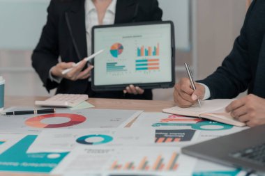 İş adamları başarılı takım çalışmalarının ve fabrika ofisinde beyin fırtınalarının sonuçlarını gösteren çizelge ve grafikleri tartışıyor. Proje planlama sunumu, yakın plan resim