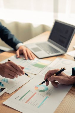 İş Meslektaşları takımı, modern ofisteki masadaki mali verileri tartışma sırasında iş stratejisi hakkında analiz eder. Masada finansal tablolar ve grafikler var. Dikey resmi kapat
