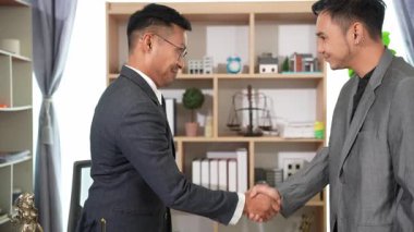Ofiste iki avukat el sıkışıyor. Hukuki belgeler, masanın üzerinde çekiç, hukuki tavsiyeler, işlemler, iş birliği toplantılarından mahkeme salonunda iyi anlaşmalara kadar..