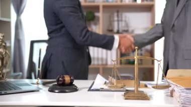 Ofiste iki avukat el sıkışıyor. Hukuki belgeler, masanın üzerinde çekiç, hukuki tavsiyeler, işlemler, iş birliği toplantılarından mahkeme salonunda iyi anlaşmalara kadar..