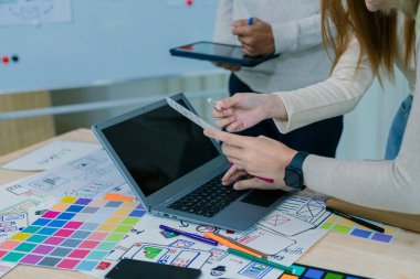 UX / UI tasarımcıları web sitesi ve mobil uygulama prototipleri ve uygulama tasarım fikirleri için beyin fırtınası düzenlerini tartışıp tartışırlar. Yakın plan..