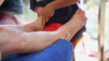 Ayak masajı. Masajcının elleri kaplıcada bir adamın bacaklarına masaj yapıyor. Kadın bir masöz tarafından geleneksel Tayland masajı, profesyonel bir masaj terapisti tarafından ayak masajı. Sağlık kavramı, rahatlama