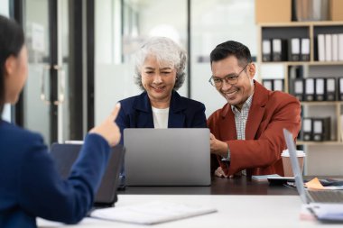 Analitik raporlar ve danışmanlar ile çalışan Asyalı iş ekibi planlar ve finansal analiz gösteriyor