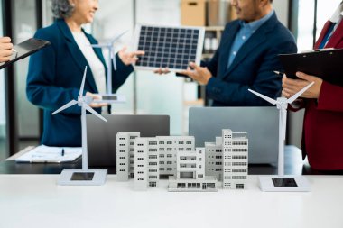 Fabrika ofisindeki mühendis ekibi, ESG proje planlaması, güneş panelleri, rüzgar türbini güç üretimi, sürdürülebilir enerji verimliliği üzerine sunum..