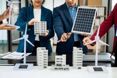 Fabrika ofisindeki mühendis ekibi, ESG proje planlaması, güneş panelleri, rüzgar türbini güç üretimi, sürdürülebilir enerji verimliliği üzerine sunum..