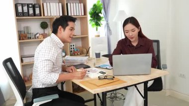 Ev konferans odasında yapılan toplantı sırasında artan satış, gelir ve kâr verilerini inceleyen ve analiz eden iki işadamı ve kadının görüntüsü.