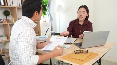 Ev konferans odasında yapılan toplantı sırasında artan satış, gelir ve kâr verilerini inceleyen ve analiz eden iki işadamı ve kadının görüntüsü.