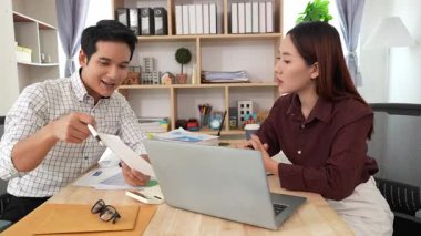 Ev konferans odasında yapılan toplantı sırasında artan satış, gelir ve kâr verilerini inceleyen ve analiz eden iki işadamı ve kadının görüntüsü.