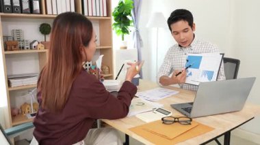 Ev konferans odasında yapılan toplantı sırasında artan satış, gelir ve kâr verilerini inceleyen ve analiz eden iki işadamı ve kadının görüntüsü.