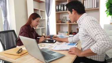 Ev konferans odasında yapılan toplantı sırasında artan satış, gelir ve kâr verilerini inceleyen ve analiz eden iki işadamı ve kadının görüntüsü.