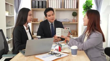 Emlakçı borç para alıyor ve bir mülk için nakit ödüyor. Emlakçı müşterilere ev planlarını sunar. Ev alırken ya da satarken karı koca.