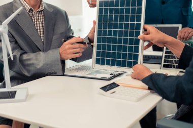 Çeşitli yaşlardaki resmi takım elbiseli iş adamları toplantıda birlikte çalışıyor, güneş çatısı hizmet projesinin pazarlanmasını tartışıyor, planlıyorlar..