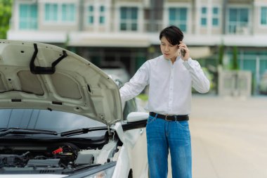 Genç bir adam sigorta acentesini aramak için telefonunu kullanıyor. Arabası bir kazada hasar görmüş..