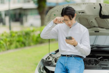 Genç bir adam sigorta acentesini aramak için telefonunu kullanıyor. Arabası bir kazada hasar görmüş..