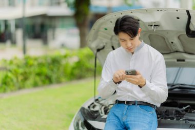 Genç bir adam sigorta acentesini aramak için telefonunu kullanıyor. Arabası bir kazada hasar görmüş..