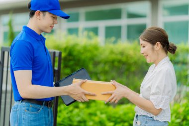 Müşteri siparişi, paket ya da teslimat servisi için mavi gömlek ve kutu taşıyan bir teslimatçı. Kadın teslimatçıdan mal alıyor..