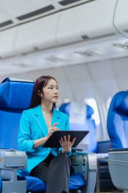Pencere kenarındaki uçakta tek başına oturup sosyal ağlardan haberler okuyan ya da uçakta seyahat uygulamaları kullanan mutlu genç bir kadın..