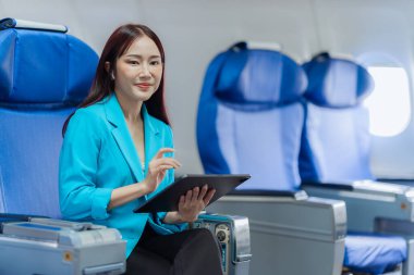 Pencere kenarındaki uçakta tek başına oturup sosyal ağlardan haberler okuyan ya da uçakta seyahat uygulamaları kullanan mutlu genç bir kadın..