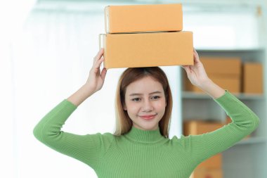 Güzel Asyalı kadın telefonda müşteri adreslerini kontrol ederken gülümsüyor. Çevrimiçi e-ticaret mağazası, ürünler satmak, nakliye.