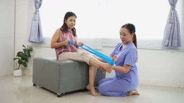 Üst düzey bir kadın, genç bir hemşireyle egzersiz yapıyor. Yaşlı bir kadına evde koltukta oturmasında yardım ediyor. Sağlık danışmanlığı, fizik tedavi konsepti.