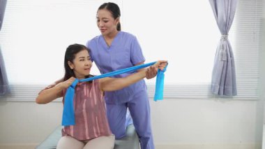 Üst düzey bir kadın, genç bir hemşireyle egzersiz yapıyor. Yaşlı bir kadına evde koltukta oturmasında yardım ediyor. Sağlık danışmanlığı, fizik tedavi konsepti.