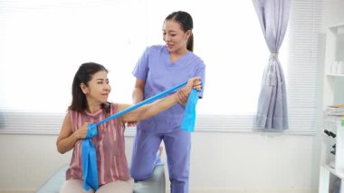 Üst düzey bir kadın, genç bir hemşireyle egzersiz yapıyor. Yaşlı bir kadına evde koltukta oturmasında yardım ediyor. Sağlık danışmanlığı, fizik tedavi konsepti.