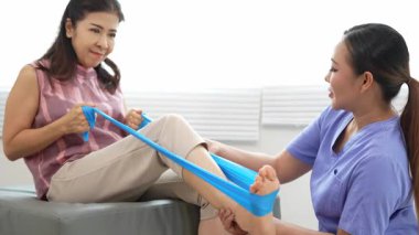 Üst düzey bir kadın, genç bir hemşireyle egzersiz yapıyor. Yaşlı bir kadına evde koltukta oturmasında yardım ediyor. Sağlık danışmanlığı, fizik tedavi konsepti.